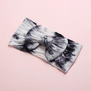 Detail of baby tie-dye nylon headband with large bow on soft ribbed cotton fabric