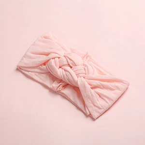 Détail du bandeau en nylon pour bébé avec un nœud torsadé rose doux et maille tricotée