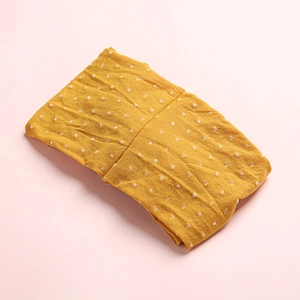 Détail du bandeau bébé en nylon jaune moutarde avec petits pois blancs et texture