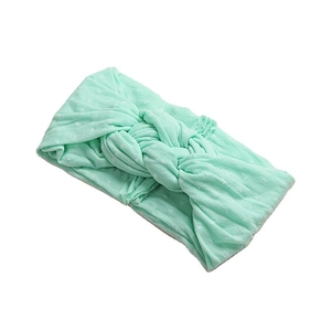 Bandeau bébé vert menthe doux avec pois et design à nœud torsadé sur fond blanc pur