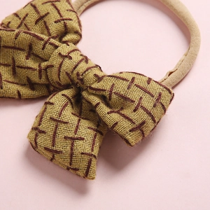 Linen texture bow hair tie for baby girls in mustard yellow with elastic nylon band