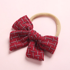 Detail of dark red linen texture bow on soft beige high elastic nylon headband for babies