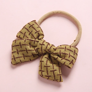 Detail showing mustard yellow linen bow headband with dark coffee plaid embroidery