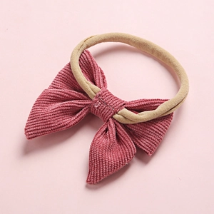 Close-up detail of soft dusty rose corduroy bow with flexible nylon baby headband texture