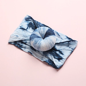 Detail of blue tie-dye nylon headband with a soft donut knot on a pink backdrop