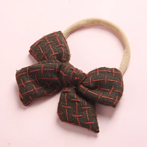 Detailed macro of dark brown linen hair bow with red cross stitching and elastic band