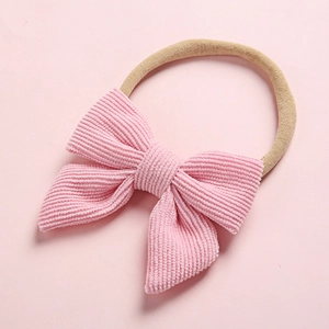 Detailed texture of soft pink corduroy bow on nylon headband for infants and kids