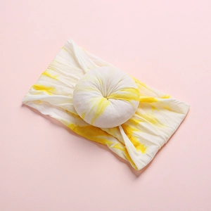 Detailed close-up of yellow and white tie-dye nylon headband with donut-shaped bow