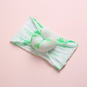 Detail of baby nylon headband featuring tie-dye donut knot on light pink surface