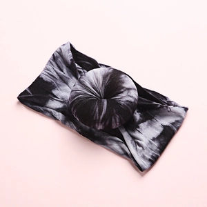 Detail of baby tie-dye nylon headband with central donut knot on a pink background