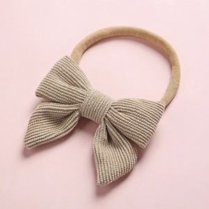 Detailed texture of beige corduroy bow on a soft nylon baby headband accessory