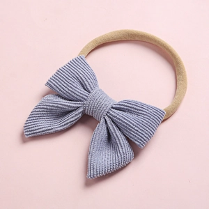 Detail of lavender corduroy bow headband with soft nylon band on pink background