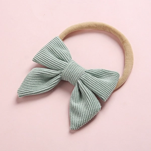Close-up of baby corduroy bow headband with soft nylon elastic band in sage green