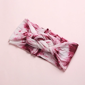 Close-up of pink and white tie-dye baby headband featuring a soft knit twisted knot detail
