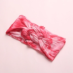 Close-up of soft tie-dye baby headband with a cross-knot design and pink fabric texture