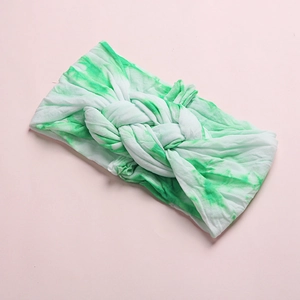Soft tie-dye infant headband with a knotted twist design on a light pink background