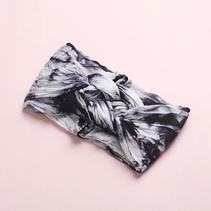 Detail of baby headband featuring black and white tie-dye soft knit fabric and knot design