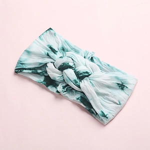 Detailed top view of a soft baby headband with green tie-dye pattern and central knot
