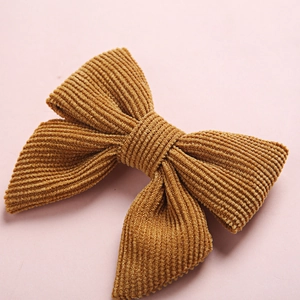 Barrette nœud en velours côtelé jaune pour filles sur fond rose minimaliste
