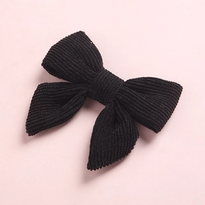 Détail d'un nœud papillon en velours côtelé noir avec texture côtelée sur fond rose