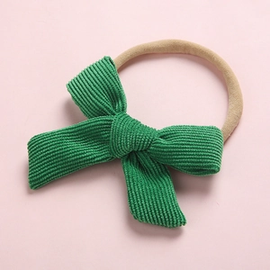 Détail d'un nœud en velours côtelé vert sur un bandeau souple en nylon pour bébé