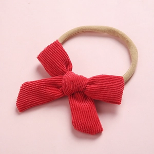 Détail d'un nœud en velours côtelé rouge et bandeau bébé en nylon beige souple