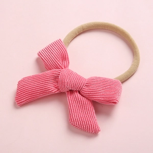 Détail d'un nœud en velours côtelé rose et bandeau élastique en nylon pour bébé