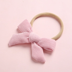 Détail du nœud en velours côtelé rose sur un bandeau bébé en nylon extensible
