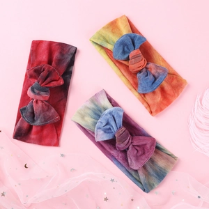 Dettaglio di tre fasce per neonati tie-dye con fiocchi morbidi su uno sfondo rosa