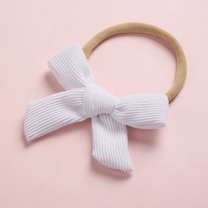 Détail d'un nœud en velours côtelé blanc sur bandeau élastique en nylon pour bébé