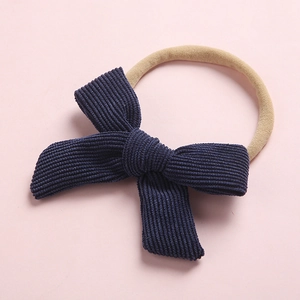 Détail du nœud en velours côtelé bleu foncé sur un bandeau souple pour bébé