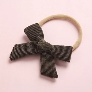 Détail d'un nœud en velours côtelé marron sur un bandeau souple en nylon pour bébés