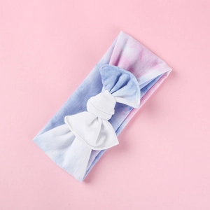 Dettaglio di una fascia morbida tie-dye per neonati con grande fiocco su sfondo rosa