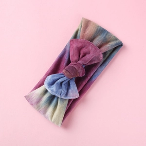Dettaglio della fascia per neonati con stampa tie-dye e fiocco su sfondo rosa