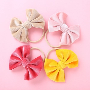 Detail von vier Samtschleifen-Stirnbändern in Gold, Rosa und Gelb für Babys
