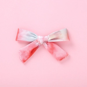 Détails macro des barrettes nœud en velours avec dégradé tie-dye rose et bleu doux