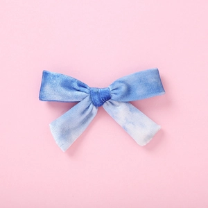 Vue détaillée du nœud en velours bleu tie-dye pour filles sur un fond rose uni
