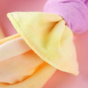 Vista macro di una fascia in maglia tie-dye per neonati in tonalità arancio e giallo