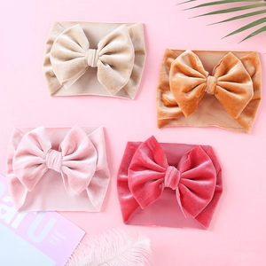 Detail of four velvet bow headbands in champagne, yellow, pink, and rose red for babies