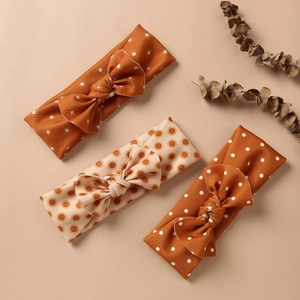 Detailed set of three elastic baby headbands with caramel bows and vintage sun patterns
