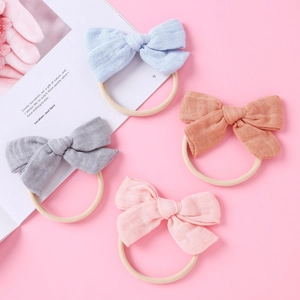 Détail de quatre bandeaux à nœud en gaze pour bébé en bleu, gris, orange et rose pastel