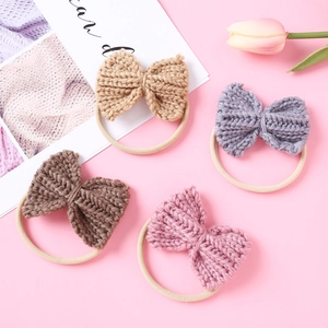 Macro detail of four knitted bow hair ties in beige, grey, brown and pink colors