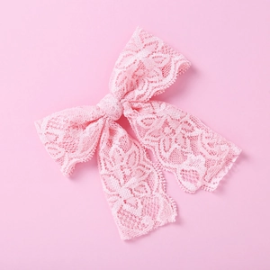 Nahaufnahme der rosa Spitzen-Haarschleife mit floralen Mustern und langen Stoffbändern