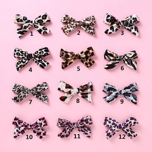 Close-up of 12-piece set of velvet leopard print bow hair clips for girls on pink background