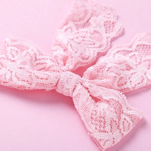 Nahaufnahme einer rosa Spitzen-Haarschleife mit floraler Textur auf rosa Hintergrund