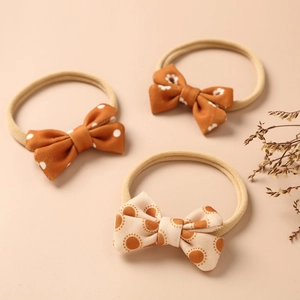Detailed set of three soft elastic baby headbands with floral and polka dot bow patterns