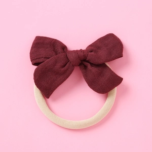 Détail d'un bandeau à nœud bordeaux texturé avec ruban en nylon beige pour bébés