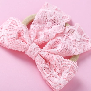 Gros plan d'un bandeau en dentelle rose pour bébé avec broderie florale délicate