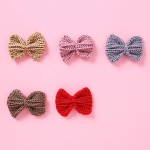 Detail of five handmade knitted bow clips in various colors with a soft ribbed texture