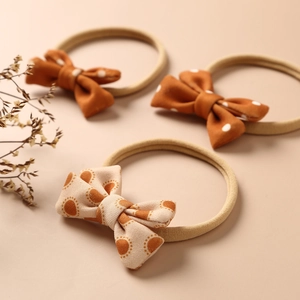 Detailed view of three baby nylon headbands with cute orange patterns and soft bows